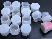 Sixteen transparent silicone furniture floor protectors displayed out of packaging, showing flexible material and perforated bottoms.