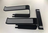 Components of the black aluminum laptop stand show concave support arms with gray anti-slip strips and a detachable vertical support piece.