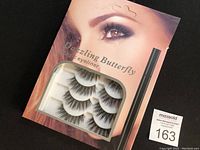 Front packaging of Dazzling Butterfly labeled box containing the adhesive eyeliner and false eyelashes set, shows an eye with makeup and 5 pairs of eyelashes visible through window.