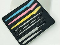 Open blackhead remover tool kit showing plastic eyebrow tweezers, stainless steel extraction tools, and brush in foam insert.