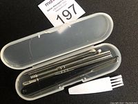 Ear wax removal kit with seven stainless steel tools in a translucent plastic case and a small white cleaning brush.
