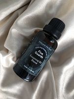 Single amber glass bottle labeled 'Natural Riches Five Guards Essential Oil Blend' placed on fabric background.