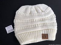 White knit winter hat displayed flat, showing detailed knit pattern and overall design.