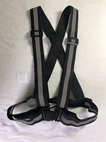 Single black reflective running vest with adjustable straps and buckles on white background.
