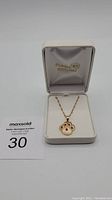 Front view of the paw pendant necklace in jewelry box with seller's auction tag
