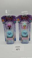 Two Hatchimals Mini Pixies Glitter Angels toys in original packaging, one pink-haired doll and one mint green-haired doll, both containing Pixies dolls inside blue egg-shaped pods.