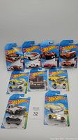 Full lot of nine Hot Wheels cars in original blister packaging displayed together on a light surface with a lot number card.