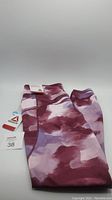 Folded leggings displaying the maroon and purple pattern with attached tags indicating size 38 and Reebok branding