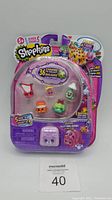Front of Shopkins Season 5 Collect and Connect Backpacks package showing five Shopkins figures and purple backpack figure.