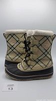 Side view of the pair of beige Sorel boots with plaid pattern, fleece lining and lace-up front.