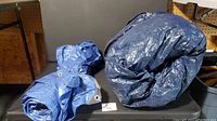 Photo showing the two tarps rolled up side-by-side, one larger and one smaller.