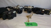 Five vintage cameras arranged side-by-side on white surface