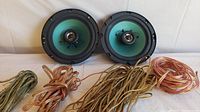 Pair of 6.5 inch teal cone speakers with copper wires coiled beside them on white surface.