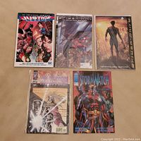 Five comic books arranged: Justice League Vol.1, Spider-Man adaptations, Wildstorm, Stormwatch
