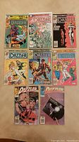 Top-down view of the 8 Dazzler comic books arranged in two rows, showing front covers with various artwork and characters.