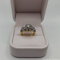 Front view of the ladies ring in a white jewelry box showing gold and rhodium plating and CZ stones.