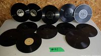 Photo showing 12 black 10-inch Edison Diamond Disc records arranged on a shelf with visible center labels.