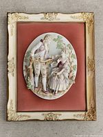 Full view of framed Victorian 3D ceramic figurines on faded velour with ornate cream and gold frame