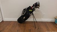 Front side view of black golf bag with clubs upright showing overall condition