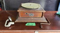 Front and side view of vintage wooden gramophone base with felt turntable, winding crank, and separate metal tonearm with reproducer.