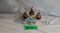Front view of full lot showing the two wine glasses, two amber Murano glass perfume bottles, ceramic figurine, and teal glass cat.