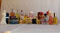 Front view of all 27 perfume bottles arranged in 2 rows on a white cloth background.