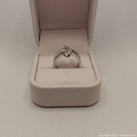 Front view of sterling silver ladies ring with diamonds inside cream ring holder.