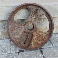 Front view of the vintage Dillon Vibrating Screen iron wheel showing the three spokes and embossed text with rust patches.