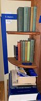 Three shelves with a collection of hardcover books, some with cloth bindings. Top shelf shows 5 field guide books. Middle shelf shows six smaller books. Bottom shelf has two large hardcover books with white tops visible.