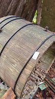 Large wooden coopered tub with metal bands showing weathering and moss.