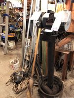 Craftsman bench grinder on pedestal with broom, rope, and other items around it in workshop