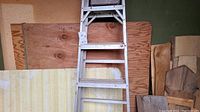 6ft aluminum ladder leaning against several wooden panels including plywood sheet 52x48in