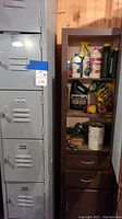 Tall gray metal locker cabinet with six individual locker doors, each with vented slats and latches, labeled with tags.