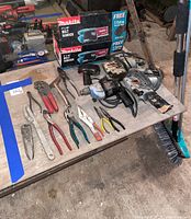 Overview of the table showing assorted hand tools, power tools including drills, jigsaws, and a Makita belt sander box.