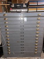 Front view of grey metal flat-file map cabinet with 12 drawers and brass handles