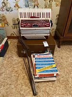 Overview of accordion on case with music books and stand