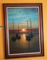 Full view of wood framed painting depicting sailboats at sunset on calm waters