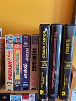 VHS tapes including John Wayne, Hero Terror, Silent Trace, Grand Canyon documentary, The Lawman, and Yosemite.