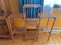 Front view of the wooden slatted plant shelf showing seven horizontal slatted shelves arranged in three levels with vertical wooden supports.