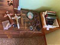 Photo showing religious items laid out, crucifixes, rosaries, candles, and books