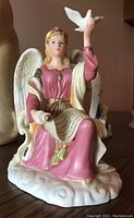 Front view of the Royal Doulton Angel of Peace figurine showing the angel holding a scroll and a dove, seated on a cloud.