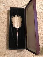 Sterling silver hairbrush in a presentation box with white bristles visible