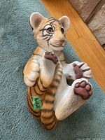 Side view of the tiger cub sculpture showing detailed face, paw pads, stripes, and realistic painting.