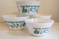 Four white milk glass mixing bowls with teal kitchen and teapot design stacked and arranged