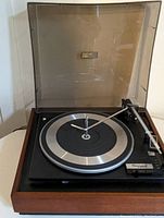 Front view of the Gerrard VIP turntable with wooden base and clear dust cover removed showing metal platter and tonearm.
