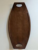 Top view of large wooden Barbocraft serving board showing smooth flat surface with curved raised edges and two cutout handles on each end for carrying.