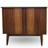 Front view of closed walnut bar cabinet showing fluted doors and tapered legs