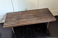 Front angle view of the wooden slatted bench showing the slatted design and the overall rectangular form.