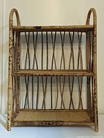 Front view of the rattan shelf showing its three woven shelves and curved side supports.