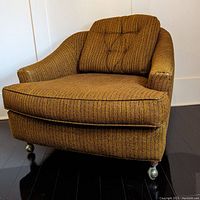 Front three-quarter view of tub chair on caster wheels, showing tufted back and seat cushion